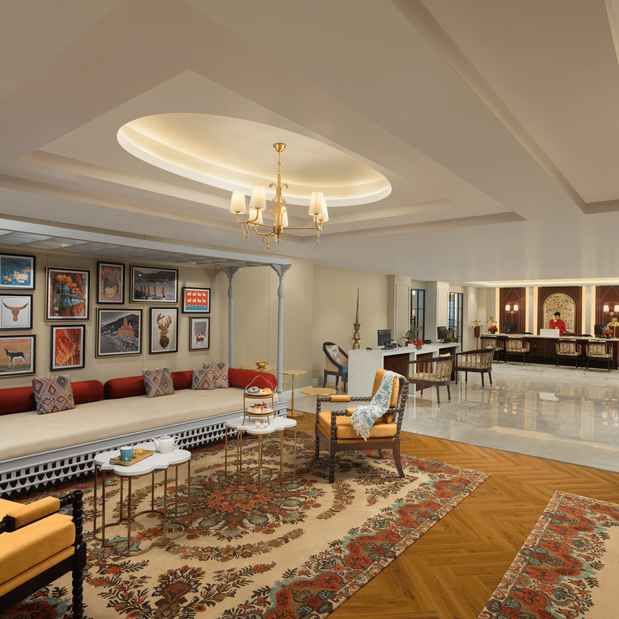 Wide view of the hotel reception desk and lobby lounge area showing polished marble floors and high coffered ceilings.