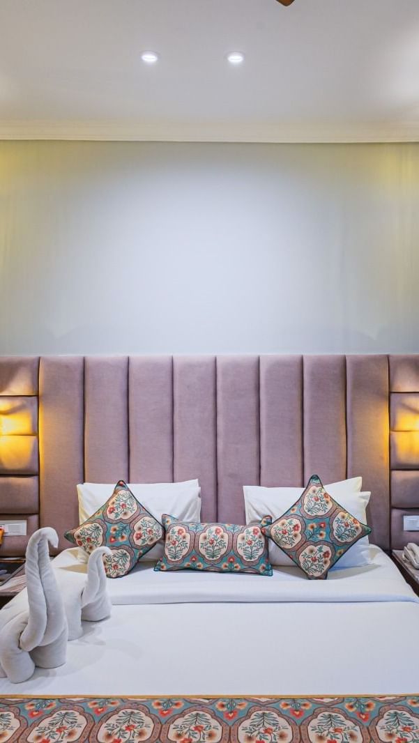 Double bed at Bamboo Saa Resort & Spa, Udaipur with upholstered headboard and towel figurines.