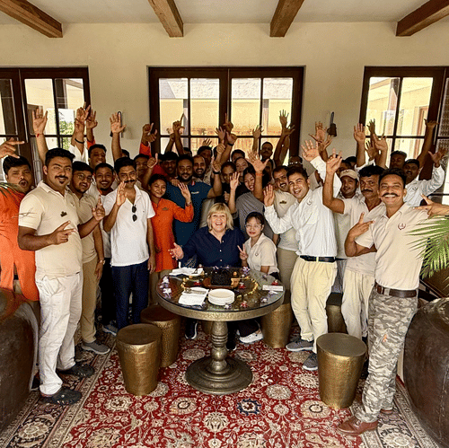 Aramness Gir team members gathered in an indoor lounge, smiling and raising their hands in celebration.