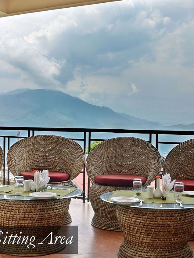 Chairs and tables that are placed in the balcony with a backdrop of clear sky | Summit Newa Regency & Spa, Pelling