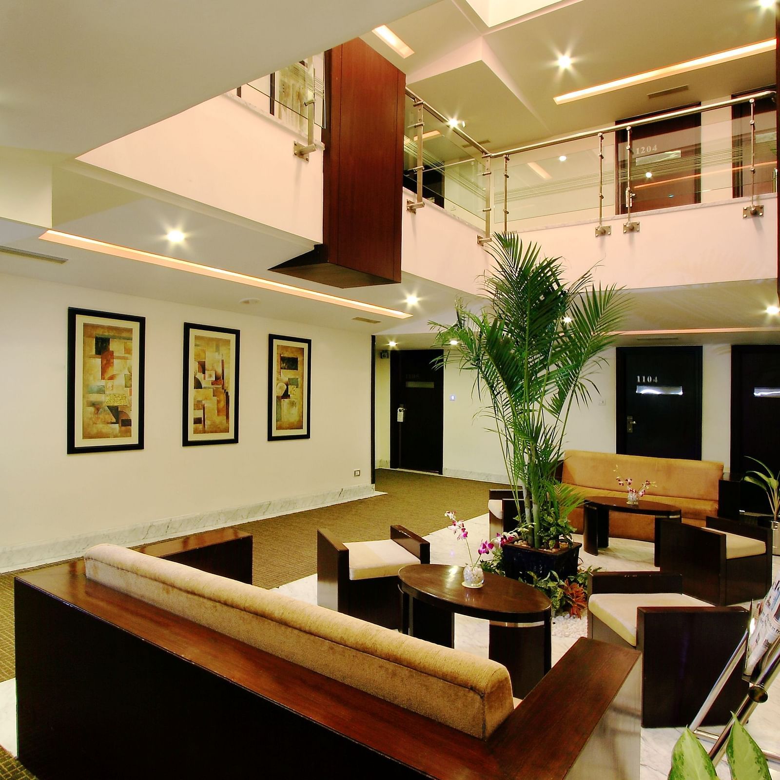 A modern and spacious hotel lobby with a two-story ceiling, framed artwork on the walls, and comfortable seating areas - The President Hotel Jayanagar, Bangalore