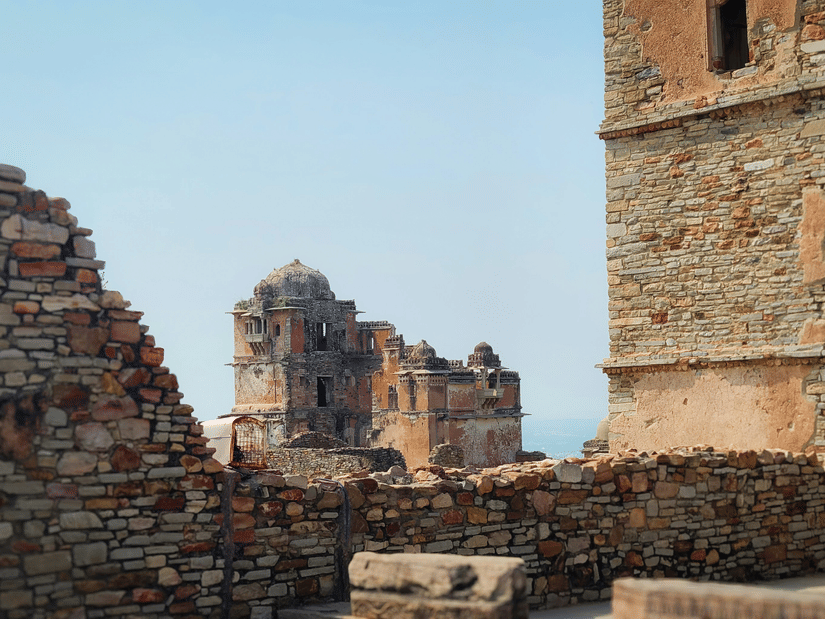 Ruined stone walls and partial structures within Chittorgrh Fort, showing erosion, broken edges, and layered masonry that reveal passage of time and history
