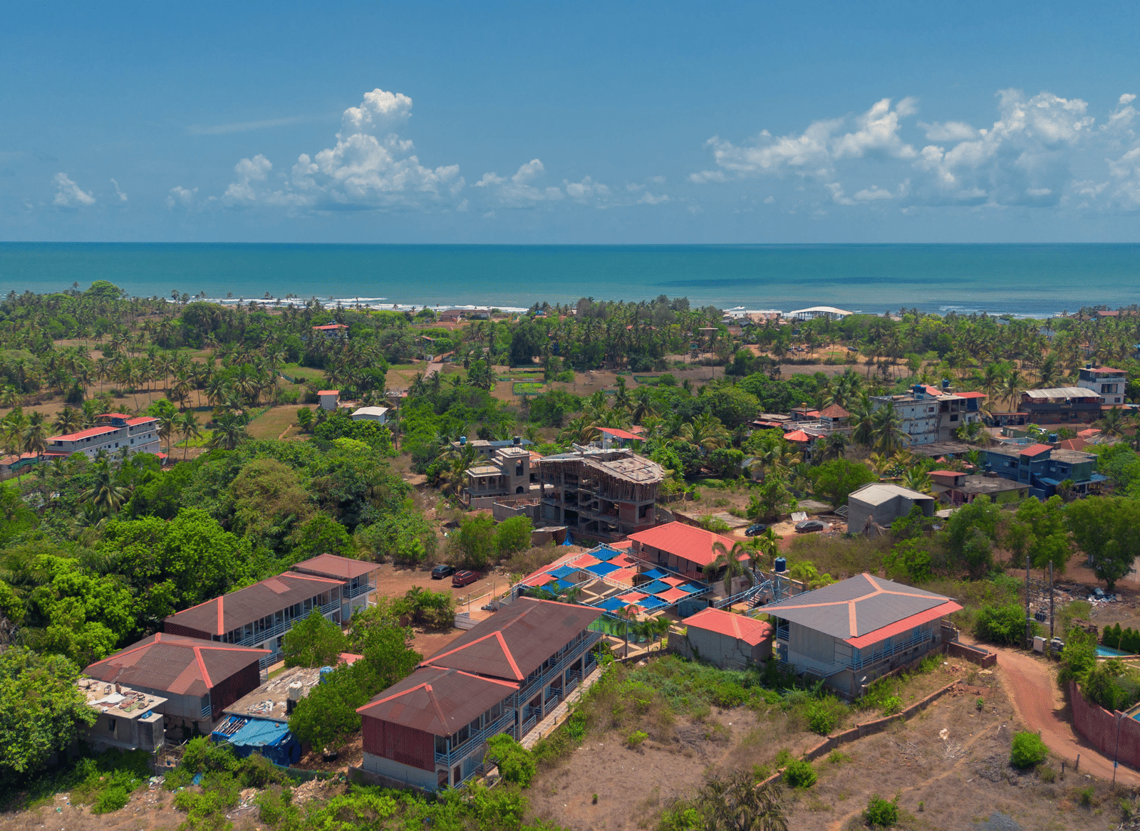 An aerial view of our resort, surrounded by lush green trees with Morjim Beach visible at the edge - Perfectstayz Koko Maya