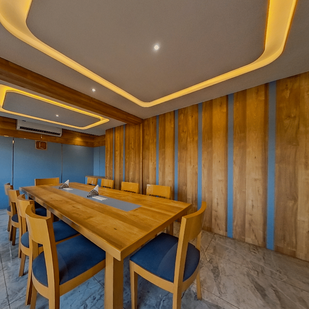 Elegant conference room at Lords Eco Inn Dahej with wooden paneling, blue upholstered chairs, and modern lighting for corporate meetings