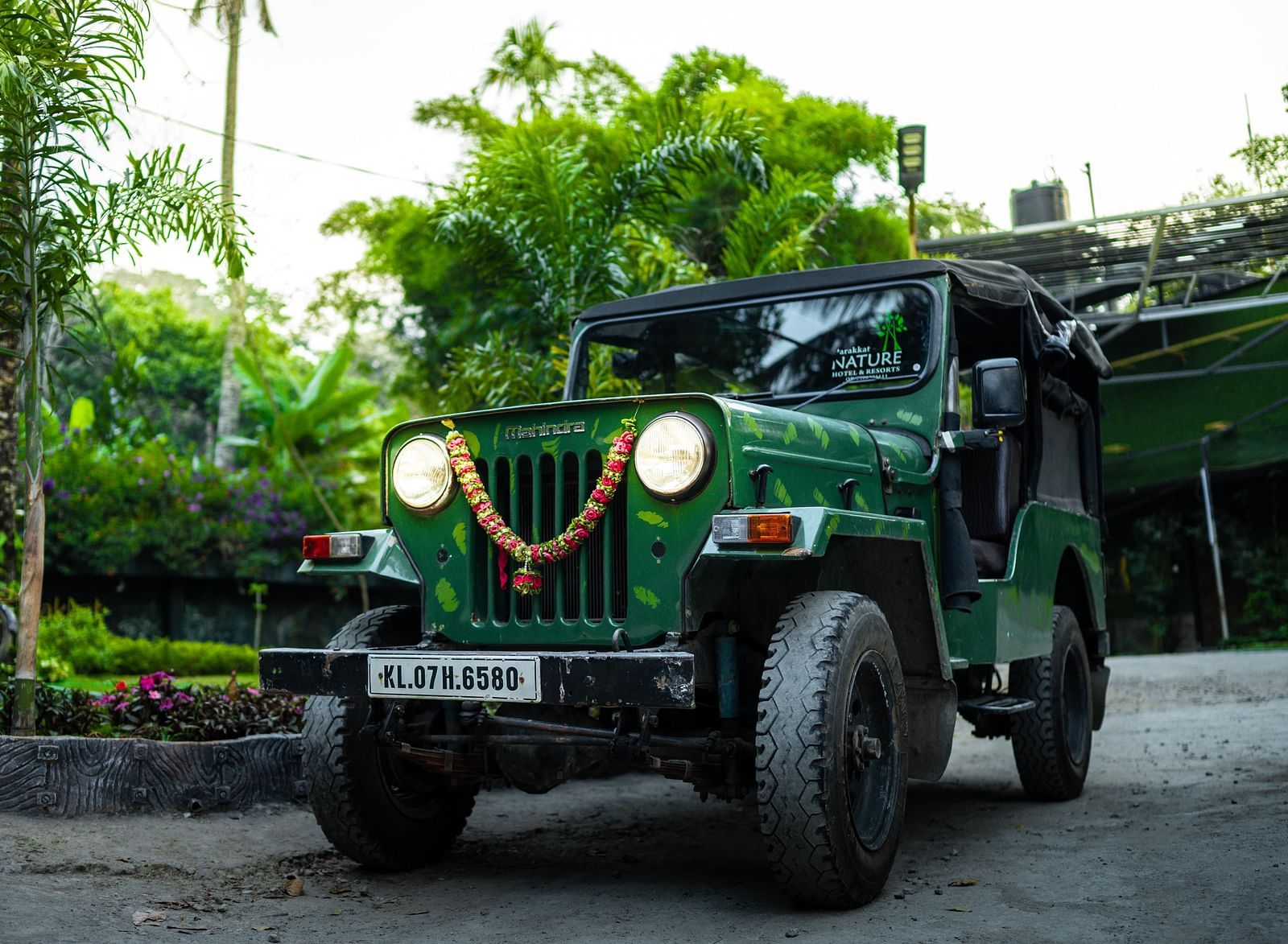 An image pf a jeep in a pathway surrounded by garden and trees