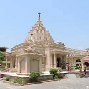 A temple with a pyramidal roof stands in a courtyard on a sunny day with trees in the surroundings