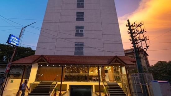 The facade of VITS Select, Bengaluru as seen from the front, featuring stairs leading up to the hotel with a vibrant sky in the background.