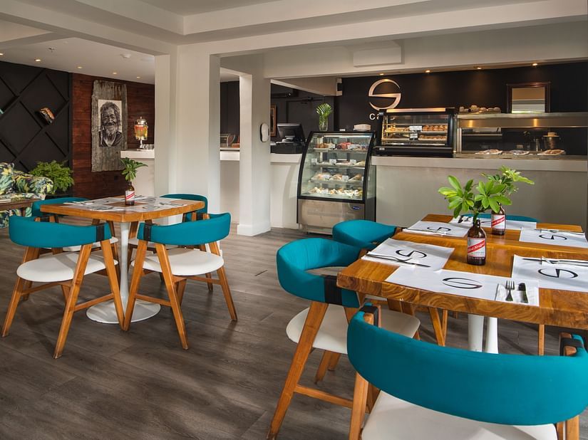 A chic cafe at our hotel in Jamaica with cosy chairs placed around wooden tables - S Hotel Montego Bay, Jamaica