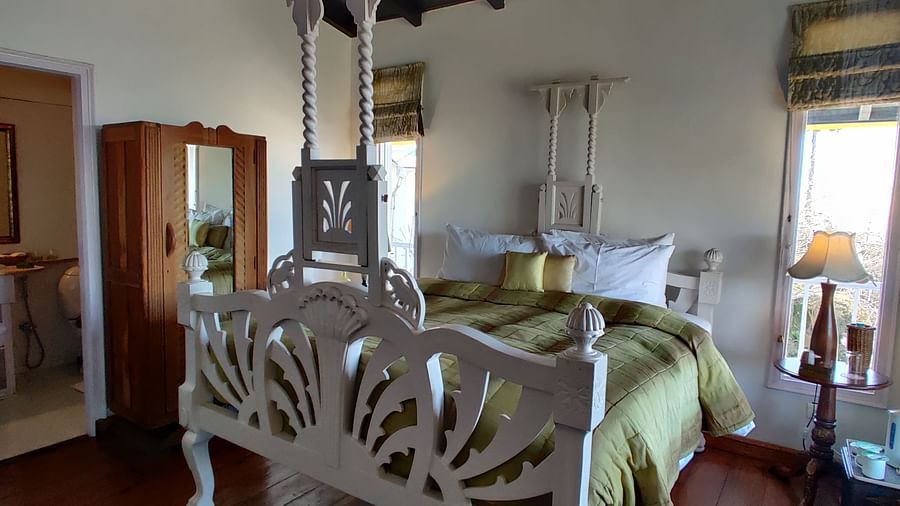 View of Premium Room with a bed with intricate frame and a door leading to the washroom at Te Aroha by Shervani Mukteshwar
