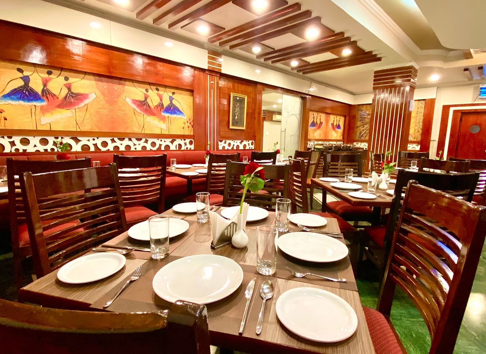 Dining area at DLS Park Grace, Haridwar featuring wooden chairs, ceramic plates, wall art and false ceiling.