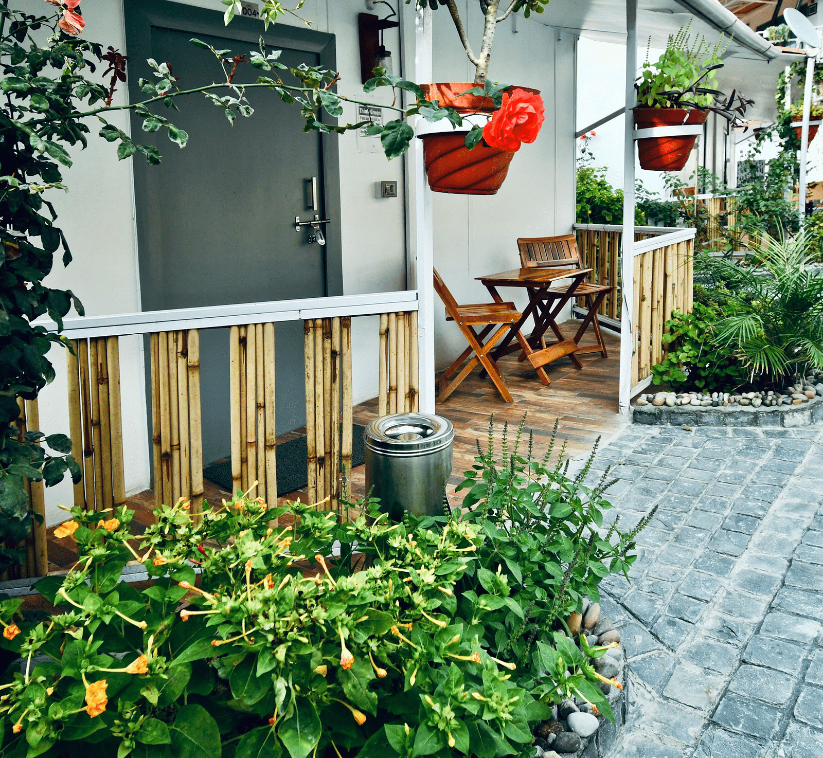 image of a porch lined with beautiful green plants with an outdoor seating area - The Tattva, Joshimath