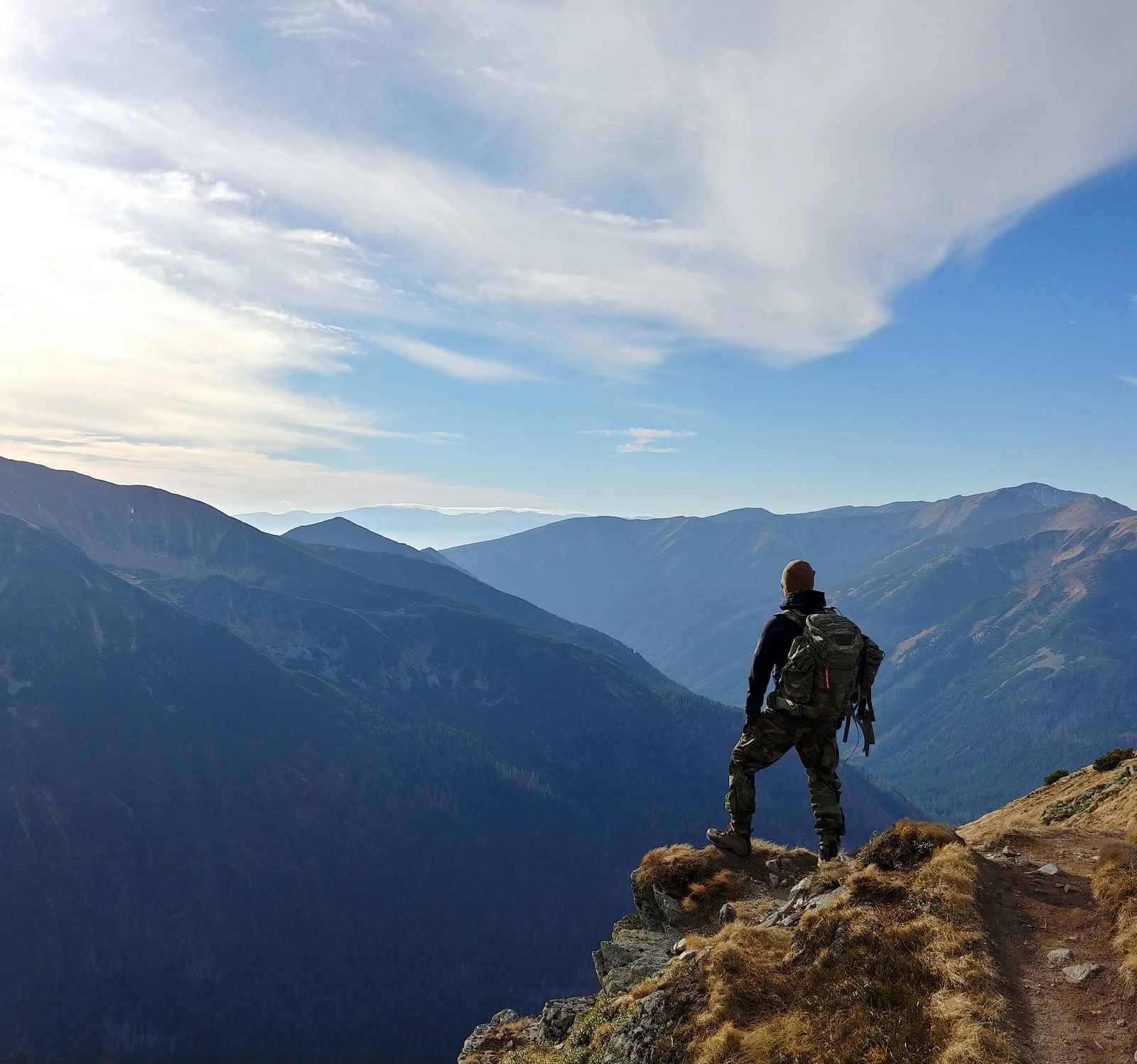A person trekking along a mountain on a cloudy day