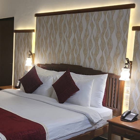  1Damanganga Valley Resorts Pvt Ltd - the king size bed with maroon pillows and a duvet offered at the Director's Suite in Daman