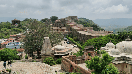 Structures and pathways inside Kumbhalgarh Fort in Rajasthan with surrounding hills visible, showing parts of the fort complex and buildings within the walls.