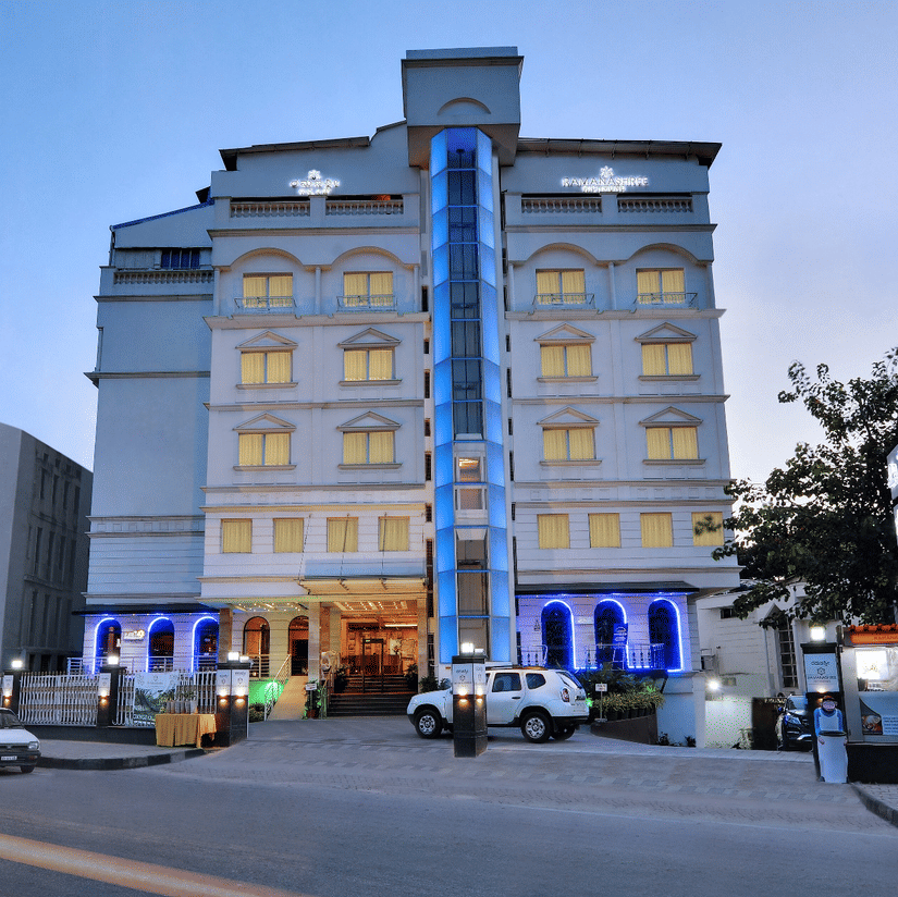 Ramanashree Richmond hotel exterior with entrance, parked cars, and lights in the evening.