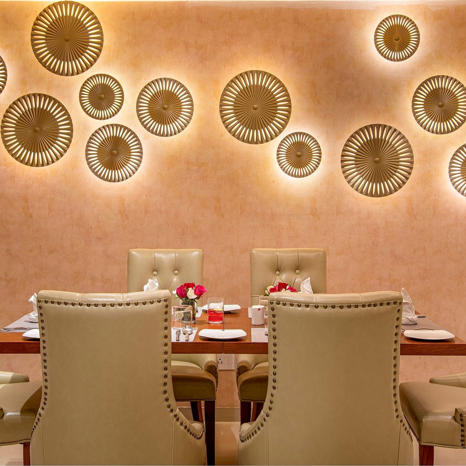 A private dining room with a decorative wall and a set table for a more intimate gathering - SK Lords Inn Ahmedabad