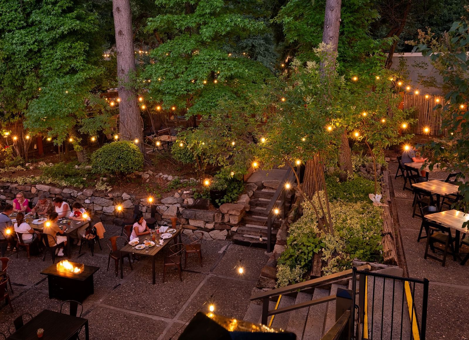 Outdoor evening dining area with guests enjoying a meal under string lights at The Groveland Hotel.