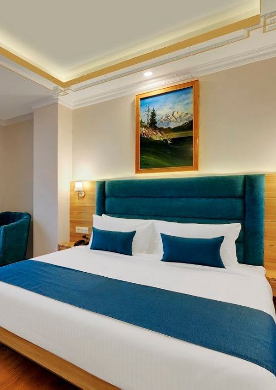 An image of the premium room with bed, bed side table, sofa, table and window overlooking the view - Yashshree Sikkim Blossom, Gangtok