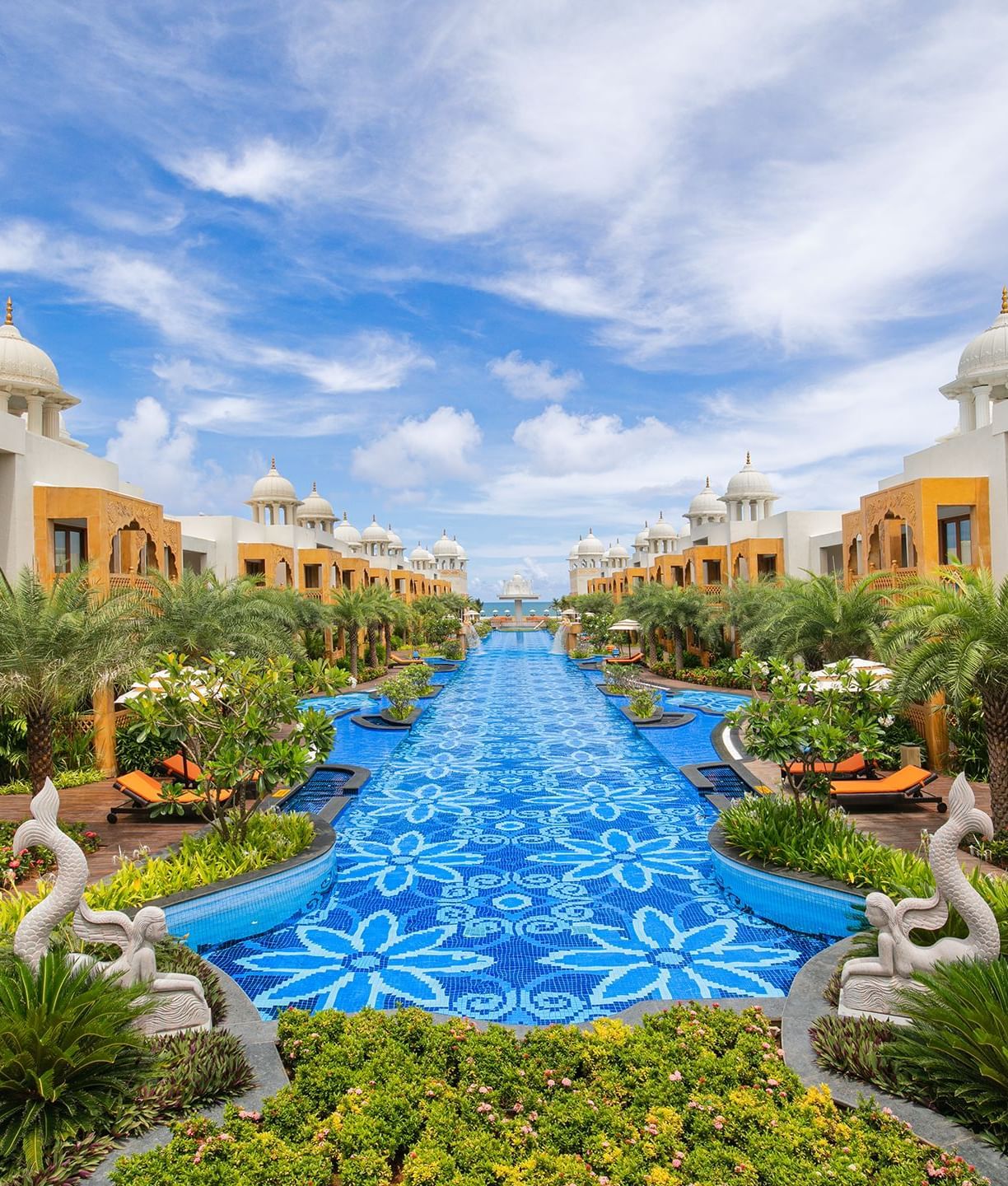 An image of a property with monumental buildings, trees, plants, and a swimming pool in between - Accord Hotels and Resorts