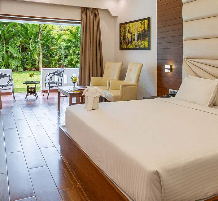 A double bed room with wooden floors, seating area, window and a door with a scenic view outside at Avana Resort