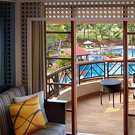 a sofa next to the balcony door inside one of the rooms - Caravela Beach Resort Goa