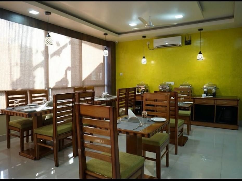 A brightly lit dining space with wooden tables and chairs, perfect for relaxed meals - Pemaling Lords Eco Inn Guwahati