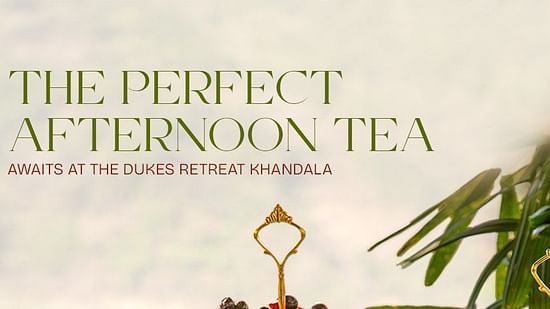 Afternoon tea setup with elegant teapots, cups, and a three-tier stand filled with colorful macarons, pastries, and savory treats at The Dukes Retreat Khandala