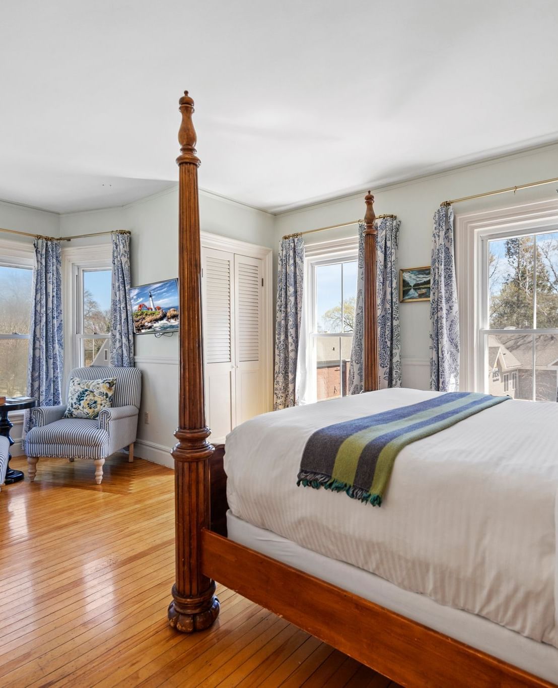 Elegant room with glass windows and dark wood four-poster bed at Hartstone Inn