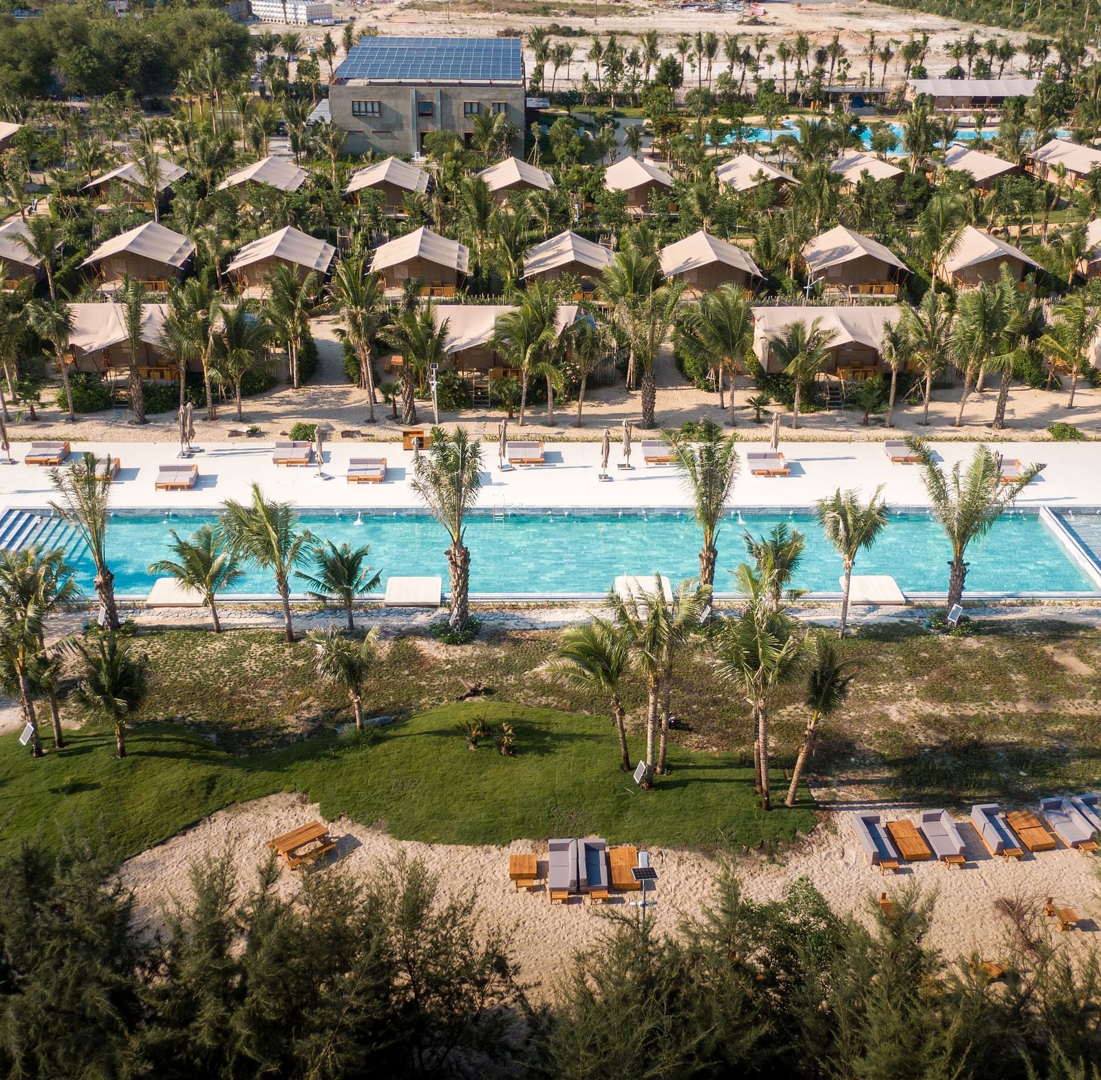 An aerial view of the pool area and surrounding greenery at WoCAL Retreat Ke Ga, showing the Mindful Tent village layout.