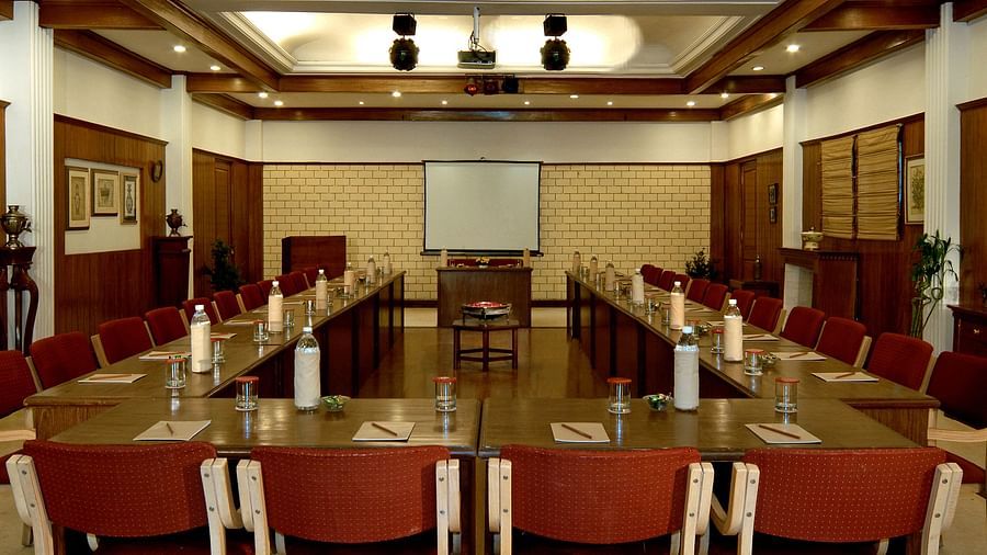 An image of Conference room with  U Shaped Set-up, a projection screen placed at the centre . The room has high ceilings, wooden paneling. The overall ambiance is professional and formal - the naini retreat, nainital.