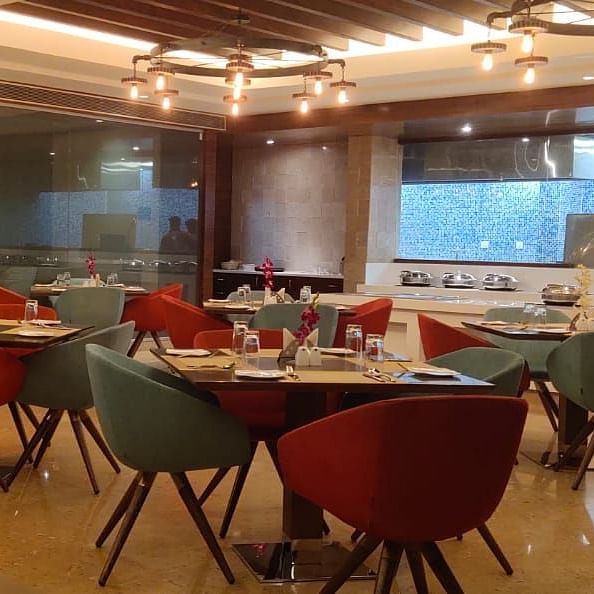 Modern restaurant dining area at Rang Lords Inn, Bharuch, with stylish chairs, set tables, and ambient lighting