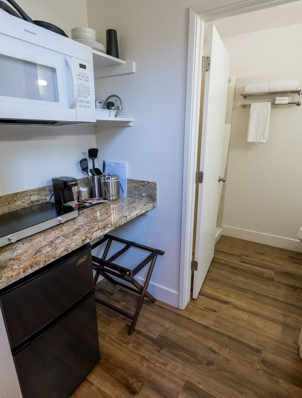 Kitchenette area at Amador Hotel featuring a granite counter, microwave, coffee station, and access to an adjoining modern bathroom.