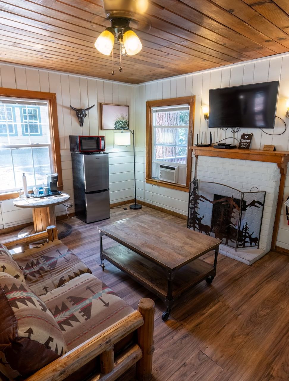 A warmly furnished living area at Serenite Hotels featuring wooden interiors, a seating area, and a wall-mounted television