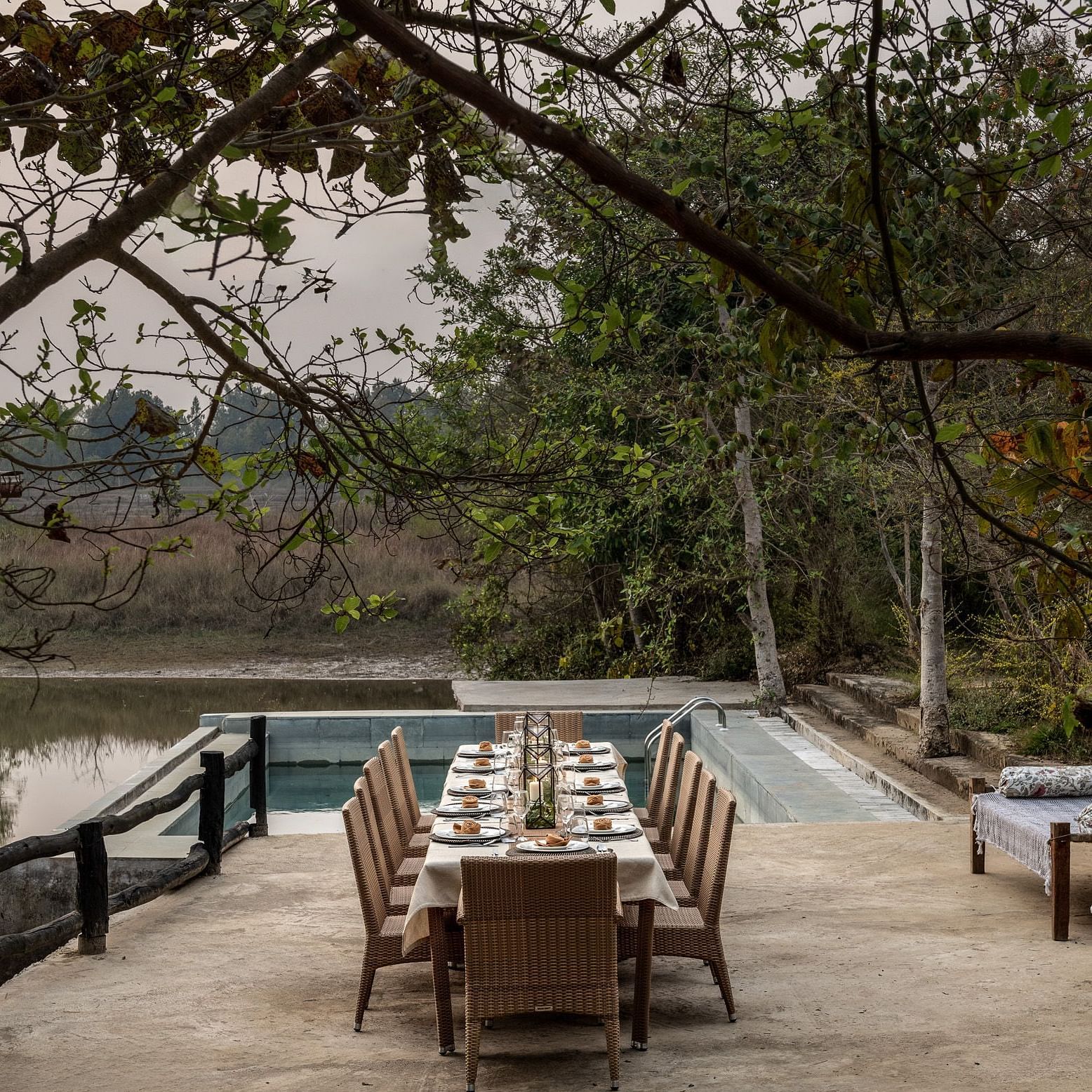 Dining setup neat Swimming Pool with a frame of beautiful trees at Saccharum Safari Lodge, Balaghat
