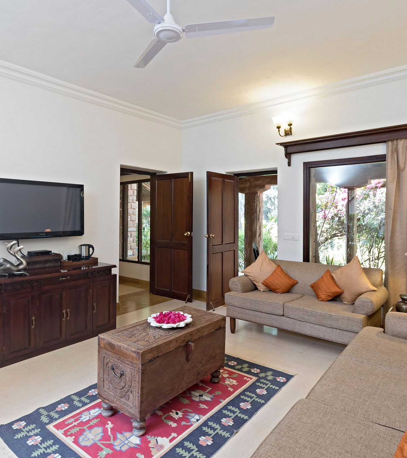 A bright and cozy living room with blue and orange cushioned sofas, a wooden coffee table, and wall-mounted decor, offering a welcoming space for relaxation - MANVAR Resort & Desert Camp
