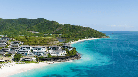An aerial view of Tamarind Hills Resort and Villas - Antigua, situated between hills, sands and pristine waters.