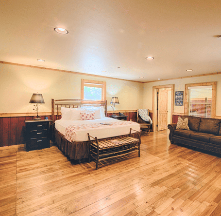 full view image of a room with a double bed along with a common seating area opposite to it - Historic Tapoco Lodge