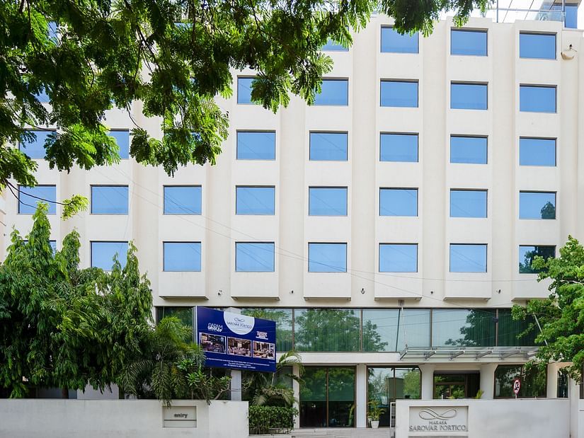  A facade image of the Marasa Sarovar Portico, Rajkot with trees around.