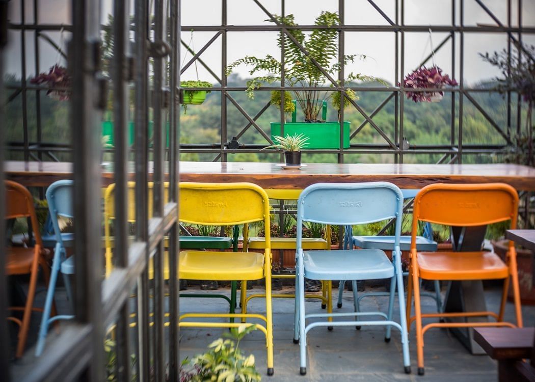 Back shot of three brightly coloured folding chairs placed in the open air dining area.