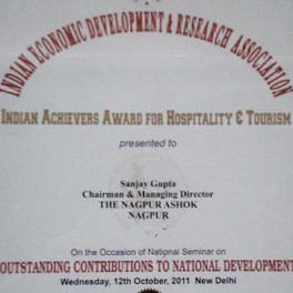 The image shows an Indian Achievers Award for Hospitality & Tourism presented by the Indian Economic Development & Research Association to the Chairman & Managing Director. - Hotel Ashok Nagpur