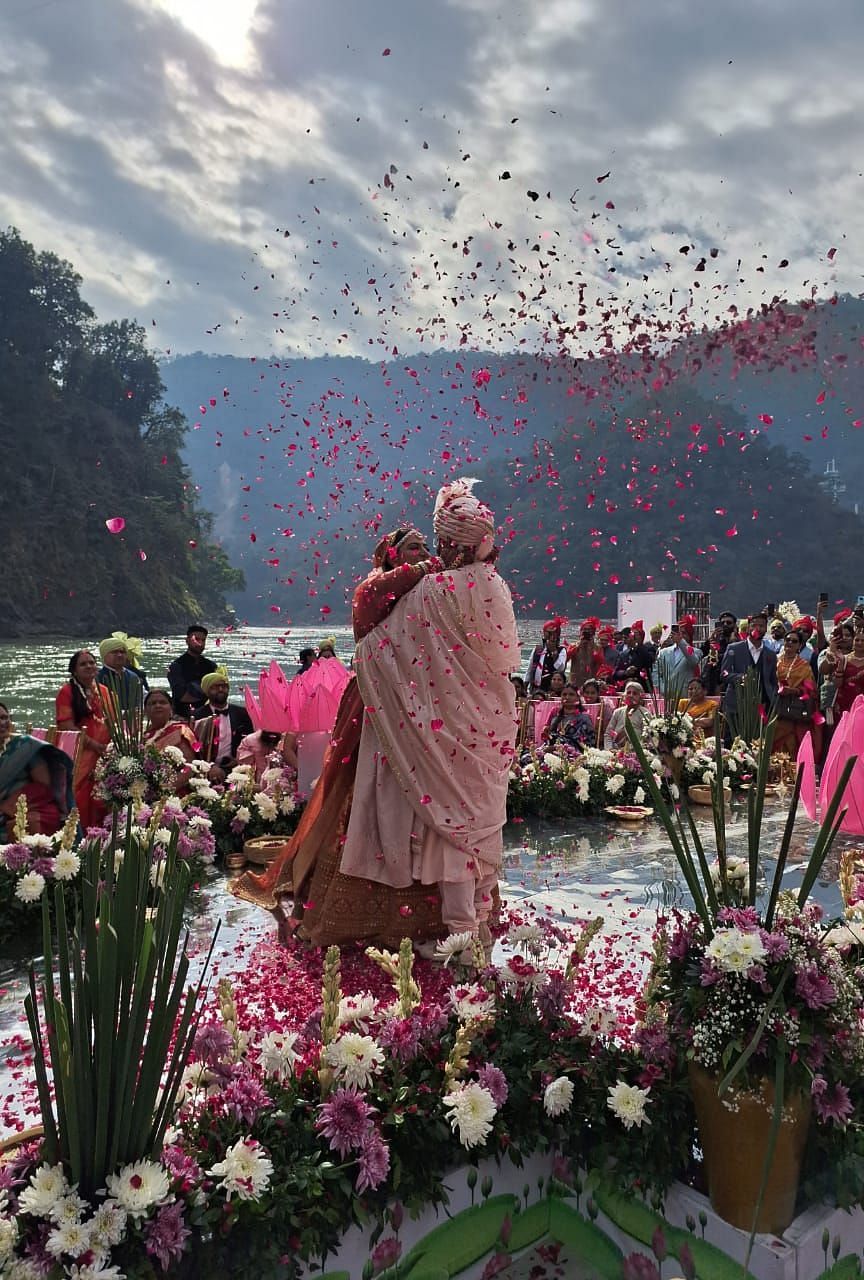 Image of a bride and groom surrounded by flowers with mountains in the background. at Aloha by the Ganges.