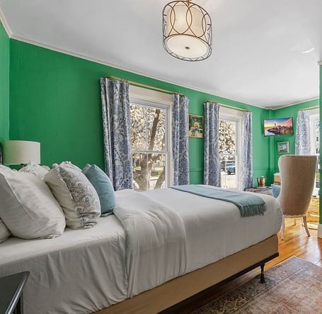 A bedroom with , green walls, and large windows lat Hartstone Inn.