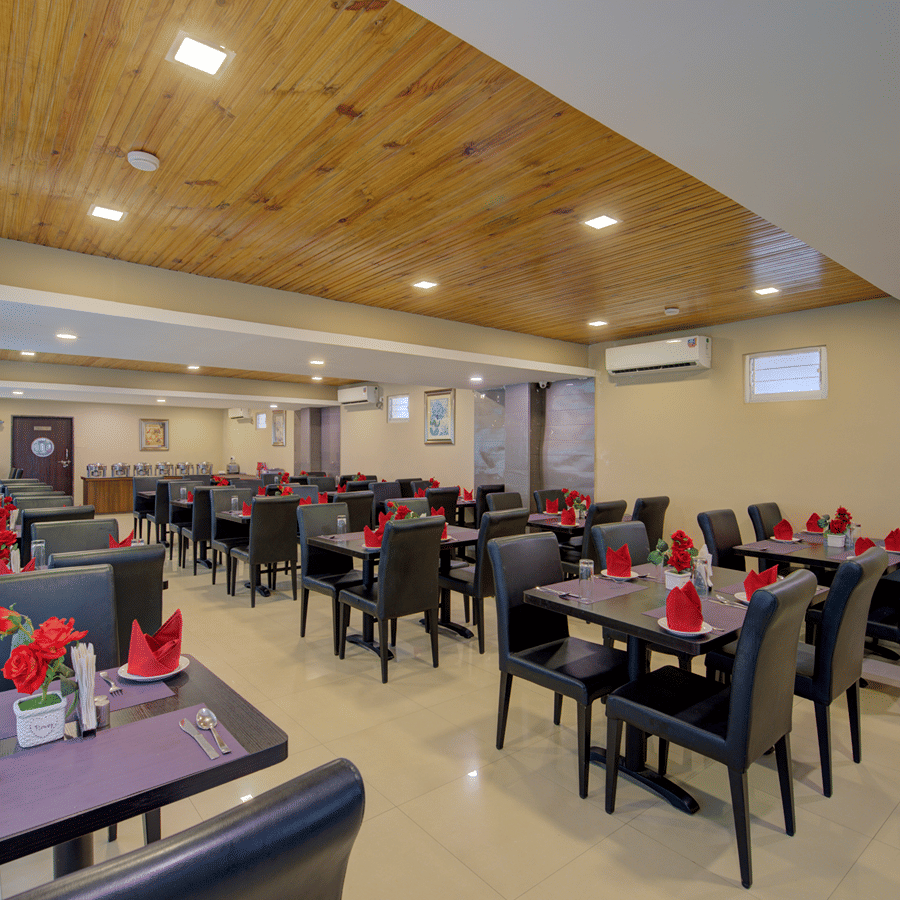 Wild Orchid Restaurant under warm lighting with empty tables and chairs at Central Courtyard Boutique Hotel, Siliguri