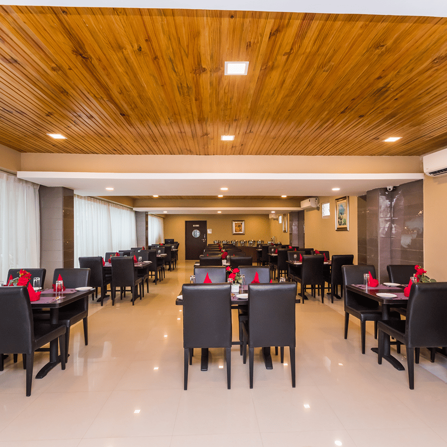 Wild Orchid, a family restaurant in Siliguri at Central Courtyard Boutique Hotel, featuring tables and chairs arranged in 3 columns under warm lighting