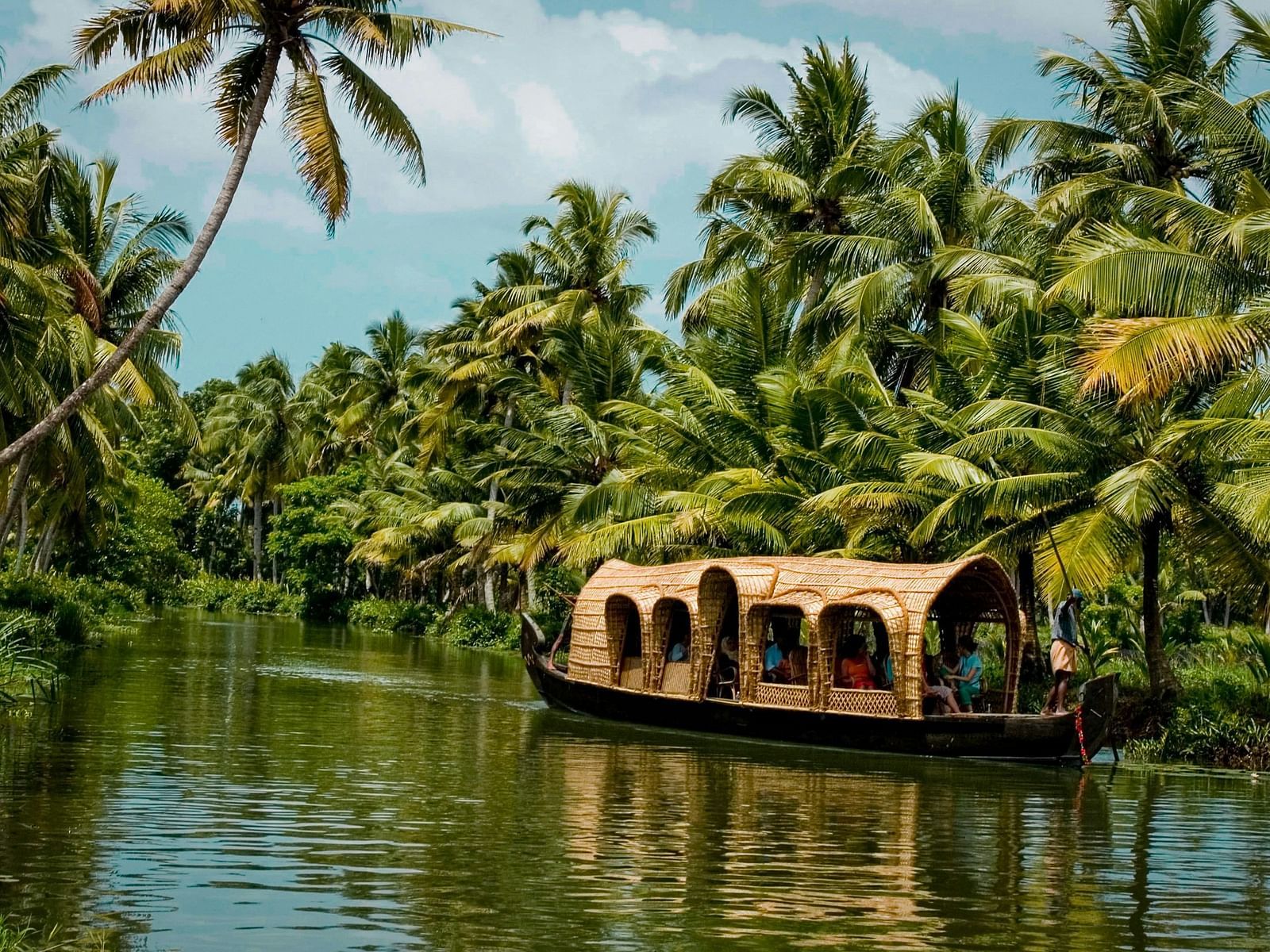 A houseboat travelling through the tranquil waters of Kerala surrounded by lush greenery
