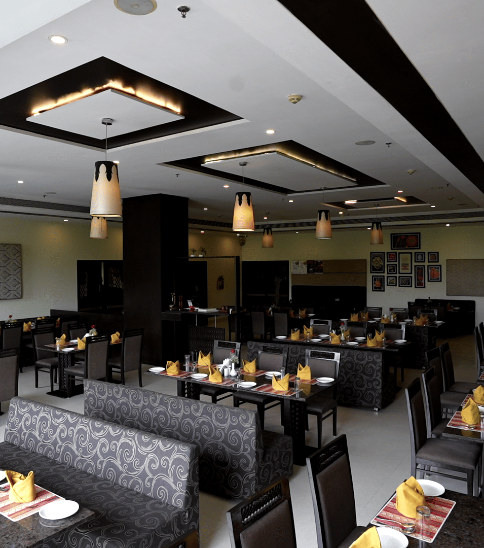 Wide-angle view of the hotel dining area with contemporary seating and lighting - Narayani Heights Hotel & Resorts