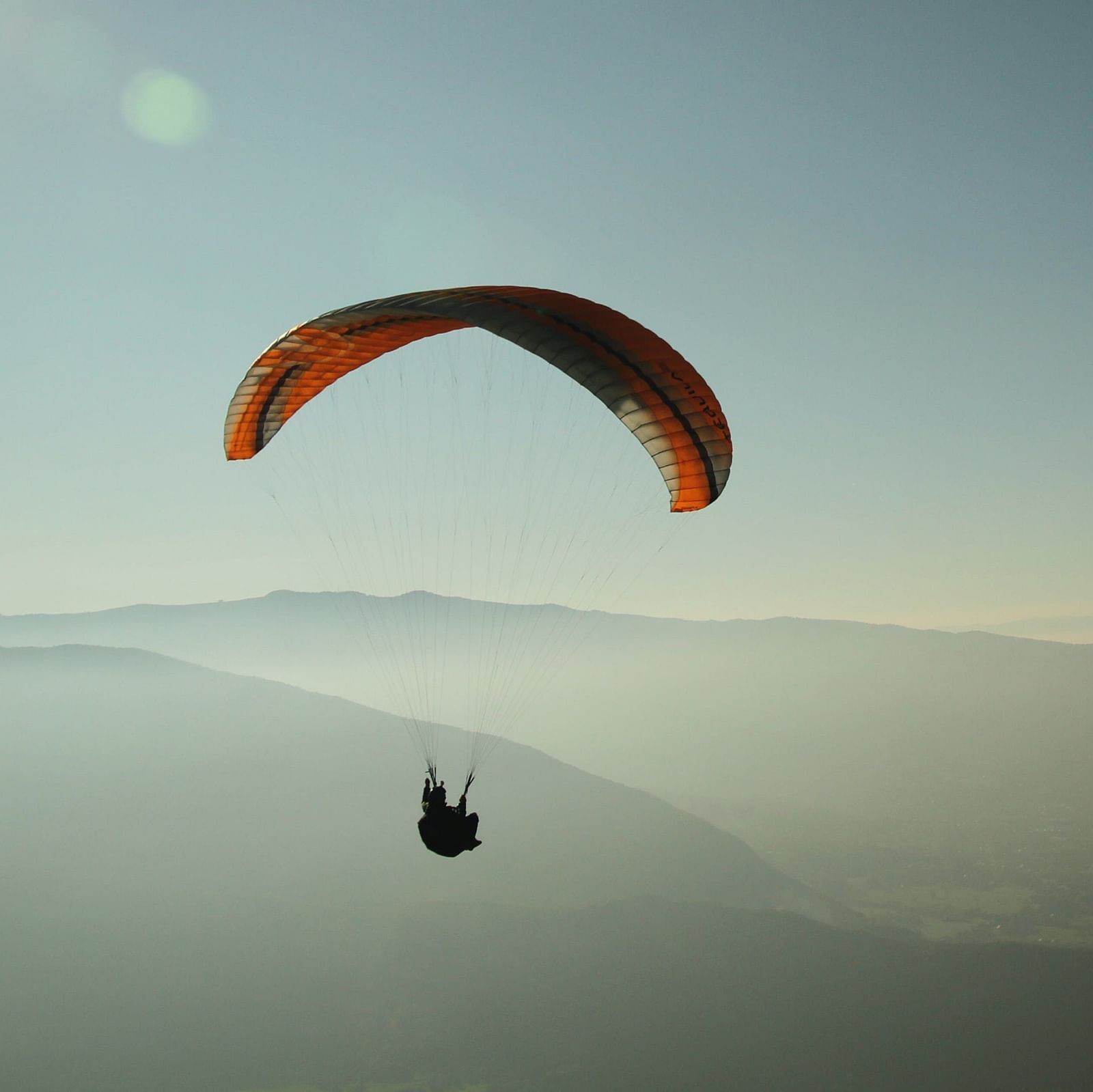 A person paragliding with a valley in the backdrop