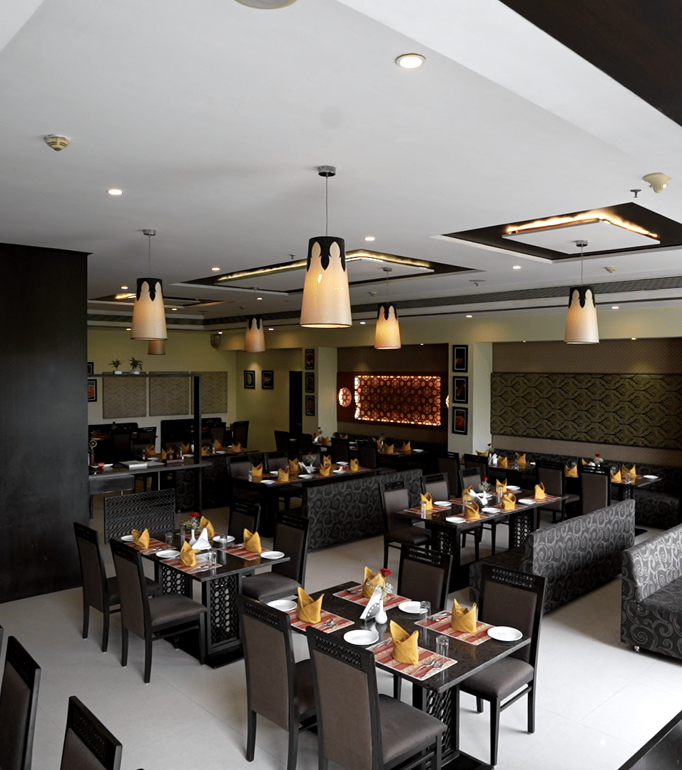 Elegant restaurant with neatly arranged tables and modern decor at Narayani Heights Hotel & Resorts, Ahmedabad.
