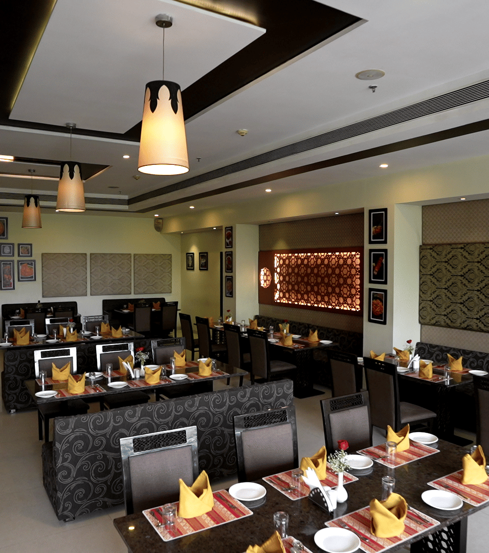 Spacious restaurant interior with ambient lighting and stylish table arrangements - Narayani Heights Hotel & Resorts