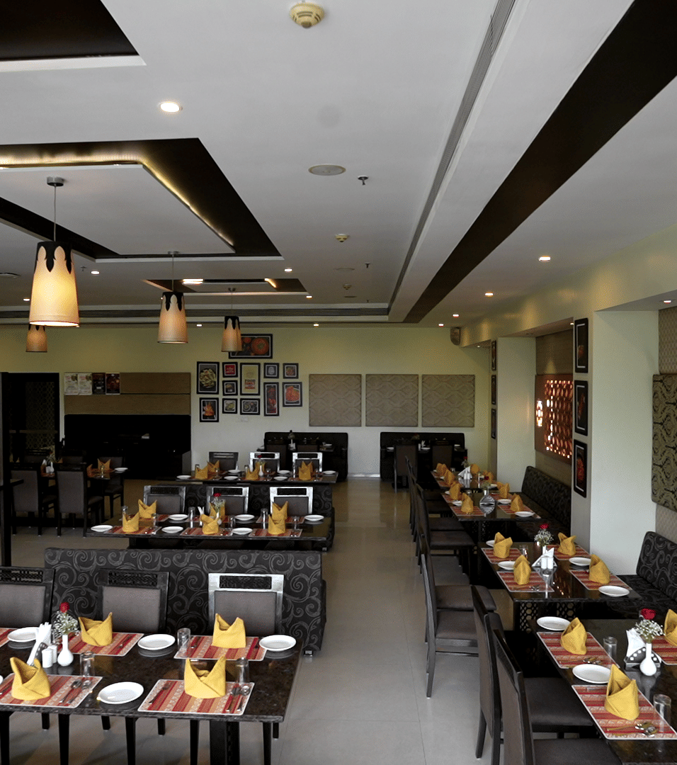 Spacious hotel restaurant with modern decor and neatly arranged tables - Narayani Heights Hotel & Resorts